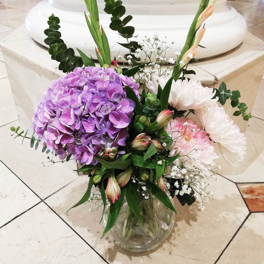 Purple hydrangea and pink rose arrangement in a glass vase