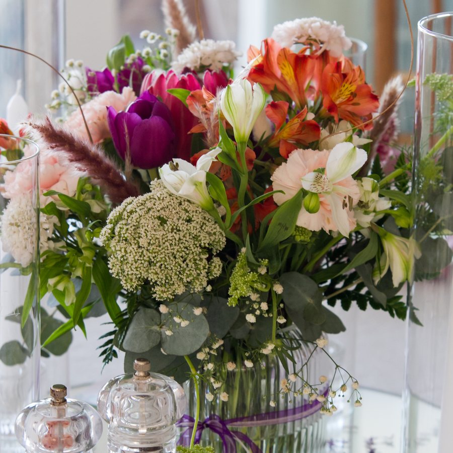 Wedding table centrepiece of tulips, alstroemeria and eucalyptus in glass