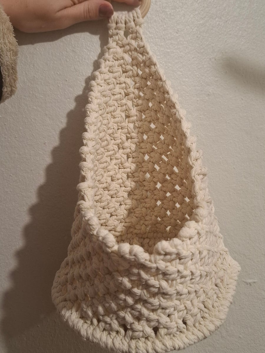 Cream macramé wall basket held up against a wall