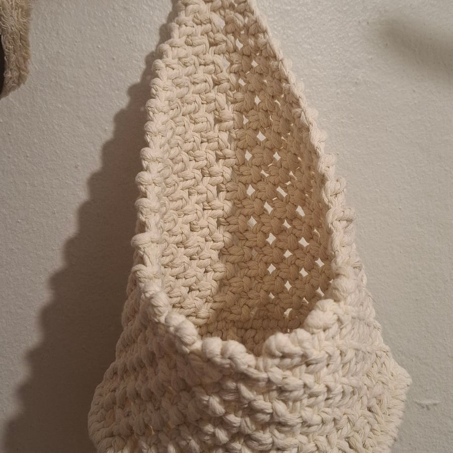 Cream macramé wall basket held up against a wall