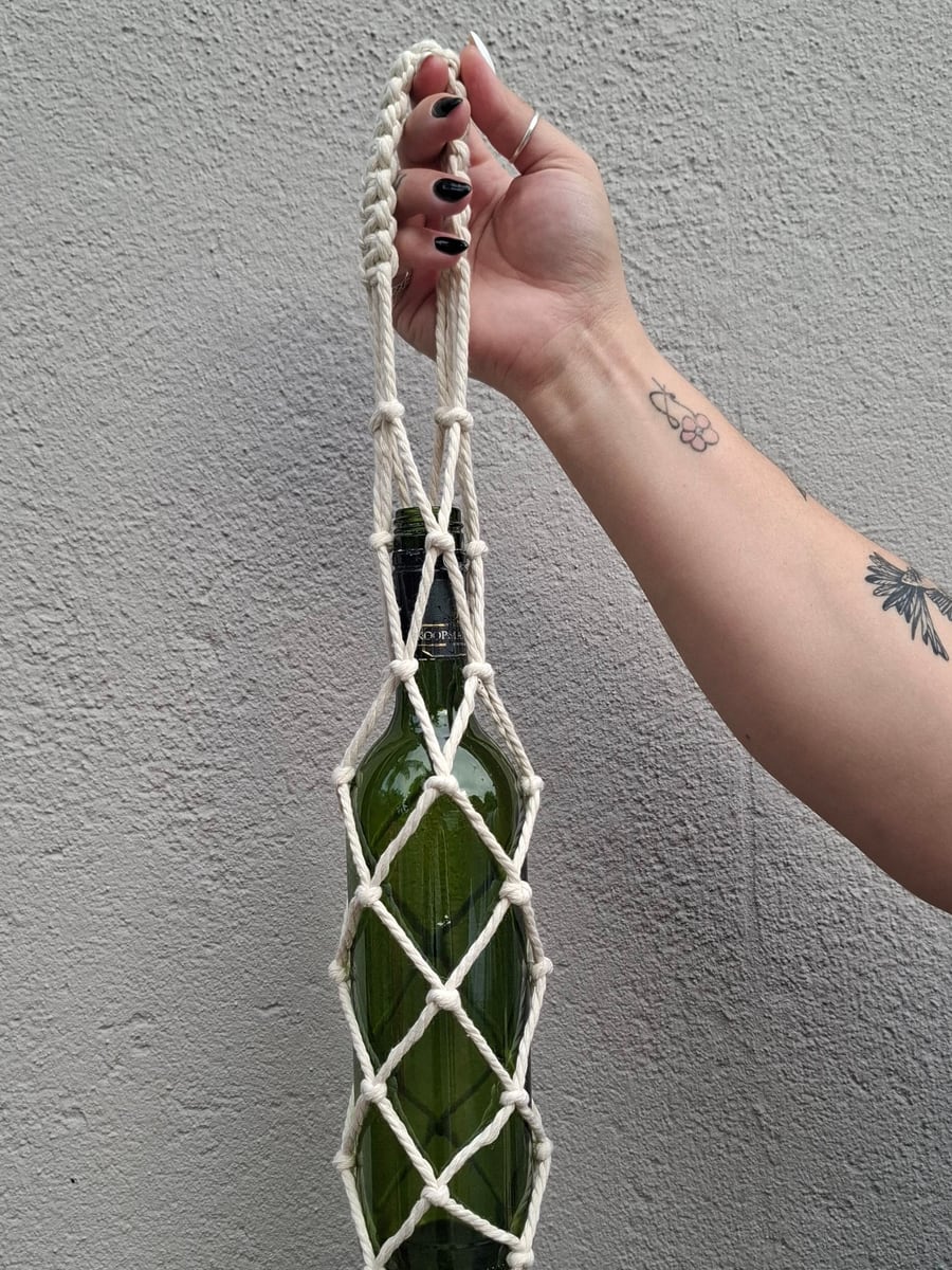 Green glass bottle in a cream macramé carrier