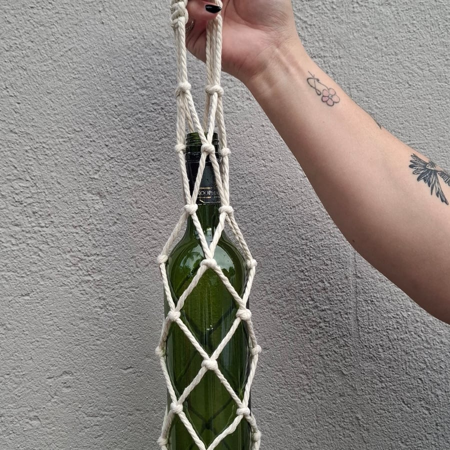 Green glass bottle in a cream macramé carrier