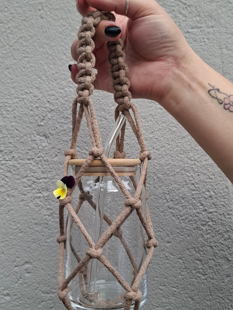 Macramé jar carrier with wooden beads, held up by hand