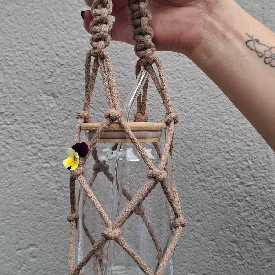 Macramé jar carrier with wooden beads, held up by hand