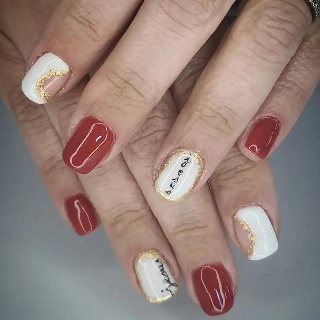 Deep red gel set with white and gold accent nails