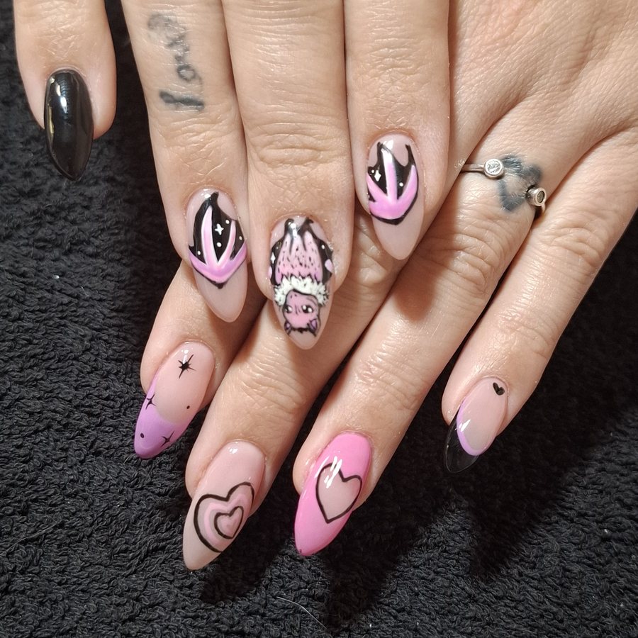 Pink and black nail art with hand-painted characters and hearts
